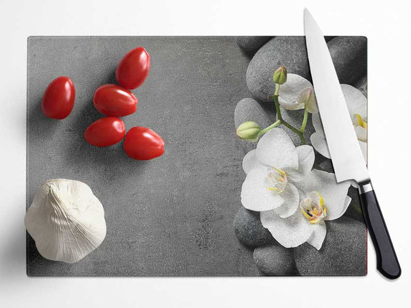 White Orchid on grey pebbles Glass Chopping Board