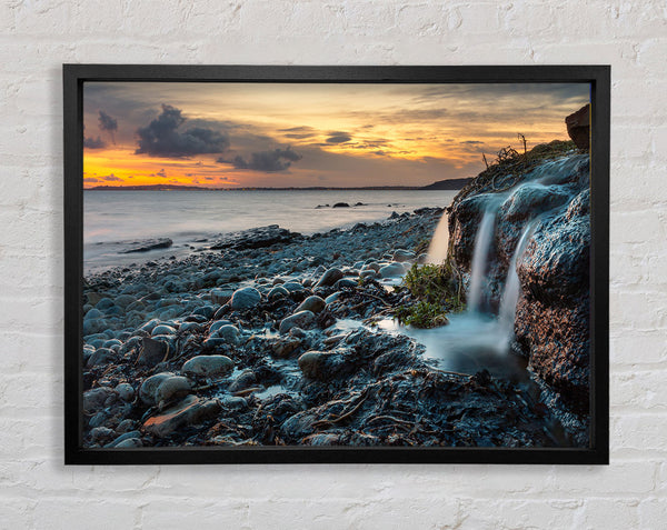 Water flows down the rocks into the sea Framed Print