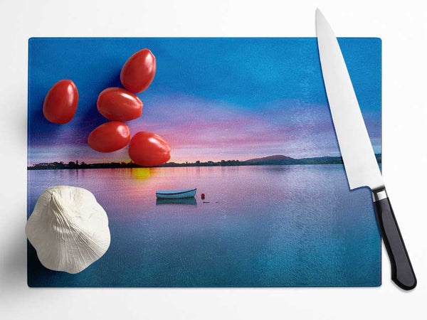 Small row boat on calm lake Glass Chopping Board