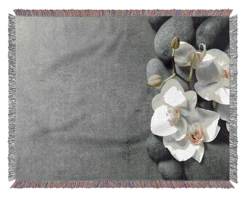 White Orchid on grey pebbles Woven Blanket