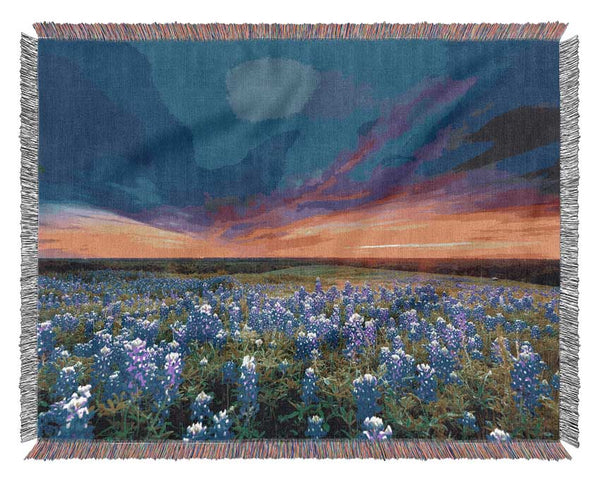 Vibrant skies above blue flowers Woven Blanket