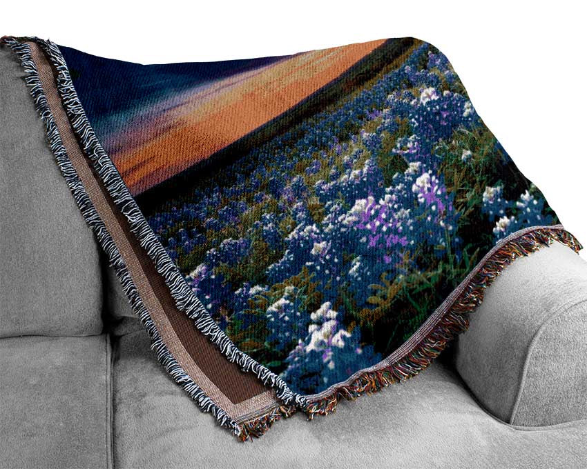 Vibrant skies above blue flowers Woven Blanket