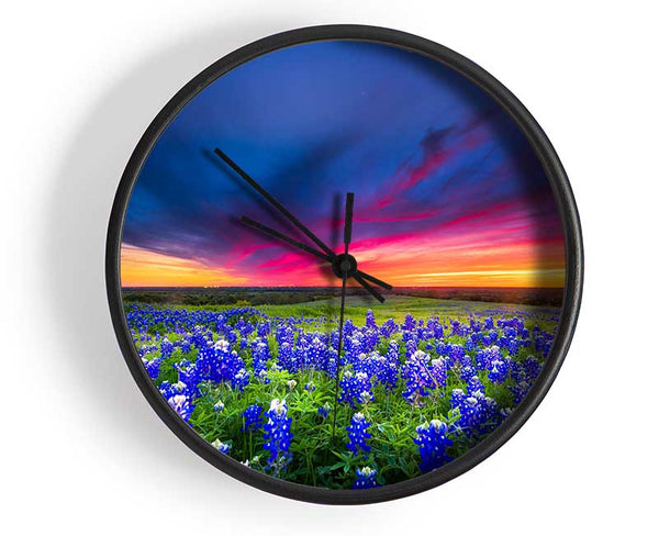 Vibrant skies above blue flowers Clock - Wallart-Direct UK